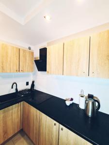 a kitchen with wooden cabinets and a black counter top at Apartament Parkowy Mrągowo in Mrągowo