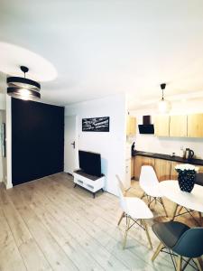 a kitchen and living room with a table and chairs at Apartament Parkowy Mrągowo in Mrągowo