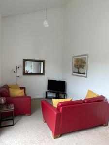 a living room with two red couches and a television at Woodside retreat holiday home in Aviemore in Aviemore