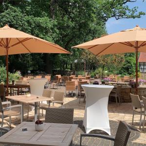 eine Terrasse mit Tischen, Stühlen und Sonnenschirmen in der Unterkunft Hotel Le Filou in Hille