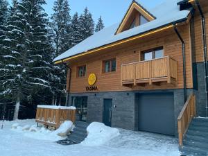 a wooden house with a garage in the snow at YASNA Apartments in Demanovska Dolina