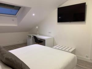 a white bedroom with a bed and a tv on the wall at Hostal Comfort Suites in Carrión de los Condes