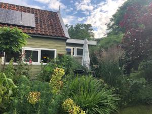 un jardín con sombrilla frente a una casa en Beemster Tiny House en Zuidoostbeemster