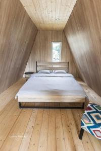 Bett in einem Zimmer mit Holzdecke in der Unterkunft Domki RWL in Rewal