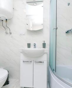 een witte badkamer met een wastafel en een douche bij Apartments Orange in Kiev