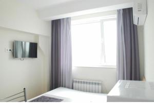 een slaapkamer met een bed en een raam met een tv bij Apartments Orange in Kiev