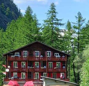 un grand bâtiment en bois avec un balcon et des arbres dans l'établissement Pension Waldegg - restaurant, à Saas-Almagell