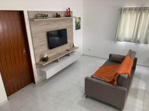 un soggiorno con un divano e una televisione di Casa Porto Fiore a Paripueira