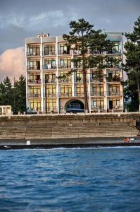 - un grand bâtiment à côté d'une étendue d'eau dans l'établissement Hotel Medusa, à Kobuleti