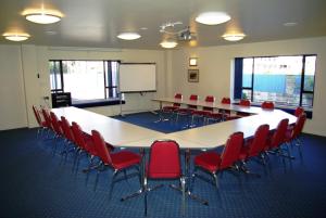 a conference room with a large table and red chairs at Abbots Hamilton – Hotel and Conference Centre in Hamilton