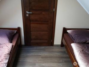 two beds in a room with a door at Zacisze in Gdańsk