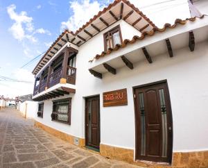 Edificio blanco con puertas marrones y balcón en Nibiru Hostel en Villa de Leyva