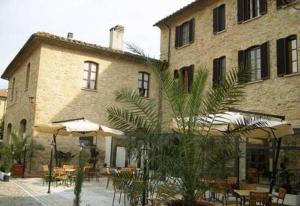 a building with tables and umbrellas in front of it at Il Vecchio Mulino in Volterra