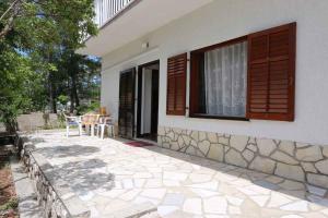 ein Haus mit einer Terrasse mit einem Fenster und einem Tisch in der Unterkunft Apartment in Silo - Insel Krk 13562 in Šilo