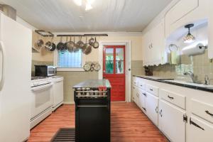 a kitchen with white cabinets and a red door at Historic Inn in the Marigny, blocks to French Quarter in New Orleans
