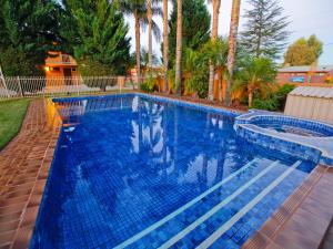a large swimming pool with blue tiles in a yard at Mildura River City Motel in Mildura