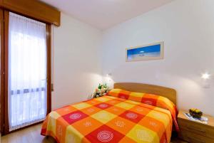 a bedroom with a colorful bed and a large window at Apartment in Bibione 24409 in Bibione