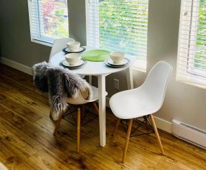 una mesa blanca con 2 sillas y una mesa con tazas en Cozy suite close to Nature and the City en Maple Ridge District Municipality