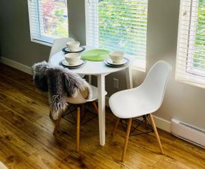 een witte tafel met twee stoelen en een tafel met kopjes bij Cozy suite close to Nature and the City in Maple Ridge District Municipality