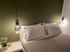 a bedroom with a bed with white pillows and two lights at B&B Home3 bed in Bisceglie