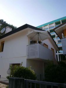 a white building with a balcony with an umbrella at Apartment in Bibione 24583 in Bibione