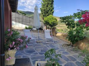 een patio met stoelen, een parasol en bloemen bij La casa del Podere in Castellaro