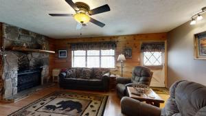 uma sala de estar com uma lareira e uma ventoinha de tecto em Heaven'S Door Cabin em Pigeon Forge