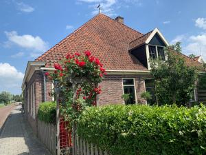 a house with a fence with red roses on it at "De Walvisch", appartement in authentieke boerderij in Edam