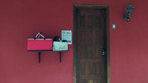 a red wall with bags on a shelf next to a door at Chalés Terras Altas de Paraty in Paraty