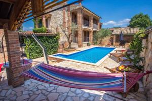 a hammock in front of a house with a swimming pool at Apartment Nova Vas/Porec 2 in Nova Vas