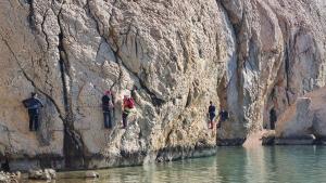 a group of people climbing a rock wall next to water at Big Blue - Xenija (Veliko Plavetnilo - Ksenija) in Metajna
