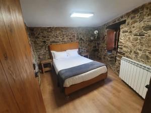 1 dormitorio con cama y pared de piedra en Casa do Talasnal Montanhas de Amor, en Lousã