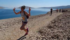 a woman running on a rocky trail near the water at Big Blue - Xenija (Veliko Plavetnilo - Ksenija) in Metajna