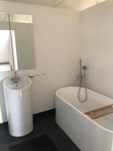 Baño blanco con bañera y lavamanos en Loft Dachsberg, en Krems an der Donau