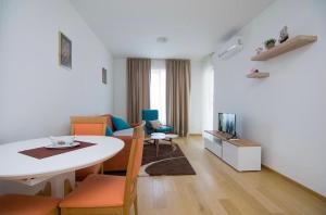 ein Wohnzimmer mit einem Tisch, Stühlen und einem TV in der Unterkunft Apartments Milica in Becici