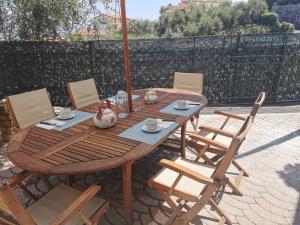 a wooden table with chairs and an umbrella on a patio at Il Viaggio in Diano Marina