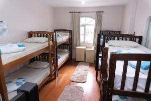 three bunk beds in a room with a window at Hostel e Pousada Tiradentes 774 in Passo Fundo