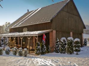 a barn covered in snow with christmas trees in front at Holiday home Vlcice 1 in Vlcice