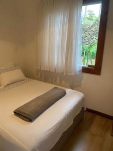 um quarto com uma cama, uma janela e uma almofada em Casa COMPLETA, 2 quartos, Estacionamento GRATUITO, WIFI 300MB, frigobar, microondas, fogão e jardim em São João del Rei