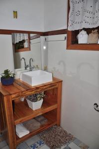 baño con lavabo blanco en una estantería de madera en Casa COMPLETA, 2 quartos, Estacionamento GRATUITO, WIFI 300MB, frigobar, microondas, fogão e jardim en São João del Rei