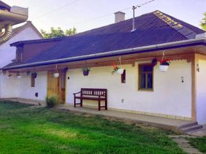 una casa blanca con un banco delante en Dorci Vendégház - A piece of peace en Cserépfalu
