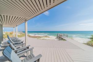 a row of chairs sitting on a wooden walkway to the beach at Nifty Shades Of Gray Home in Inlet Beach