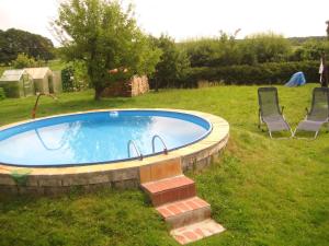 a swimming pool in a yard with two lawn chairs at Holiday home Kamminke/Insel Usedom 3203 in Kamminke