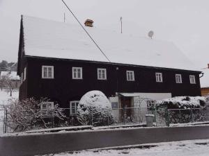 une maison noire avec un toit recouvert de neige dans l'établissement Rekreacni dum s velkou zahradu a venkovnim bazen, à Frýdlant