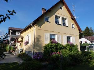 żółty dom z kwiatami przed nim w obiekcie Holiday home Vrchlabi/Riesengebirge 2190 w mieście Podhŭří
