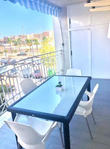 einen Glastisch und weiße Stühle auf dem Balkon in der Unterkunft Apartamento Santa Pola"The Guitar" 300 m de la playa in Santa Pola