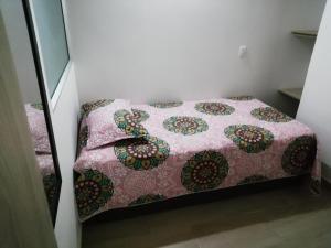 a small bedroom with a bed with a pink quilt at Apartamento La Ceja in La Ceja