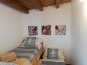 a room with two beds and paintings on the wall at Casa Veronica in Marzamemi