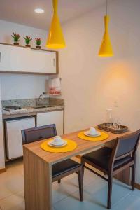 cocina con mesa de madera, sillas y luces amarillas en Flat Completo para uma estadia perfeita NOTA FISCAL en Campos dos Goytacazes