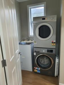 een wasmachine en droger in een badkamer met een wastafel bij Outback on Broadway in Picton